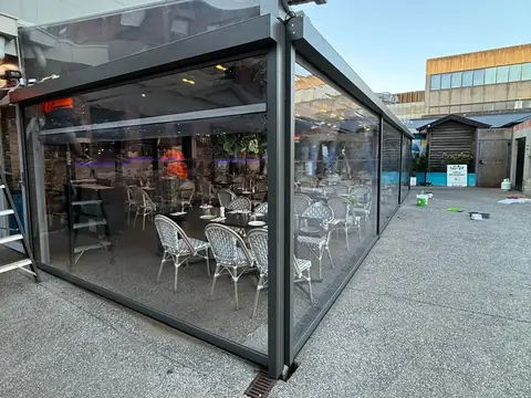 Clear PVC screens enclosing a cafe's outdoor dining area, tables set inside