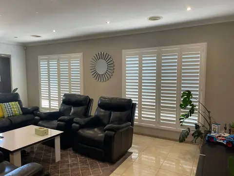 White plantation shutters across a living room window